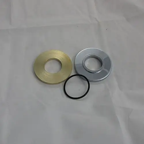 Drei runde Metallteile in verschiedenen Farben (gold, chrom und schwarz) auf hellem Hintergrund, möglicherweise Ersatzteile von Kludi.